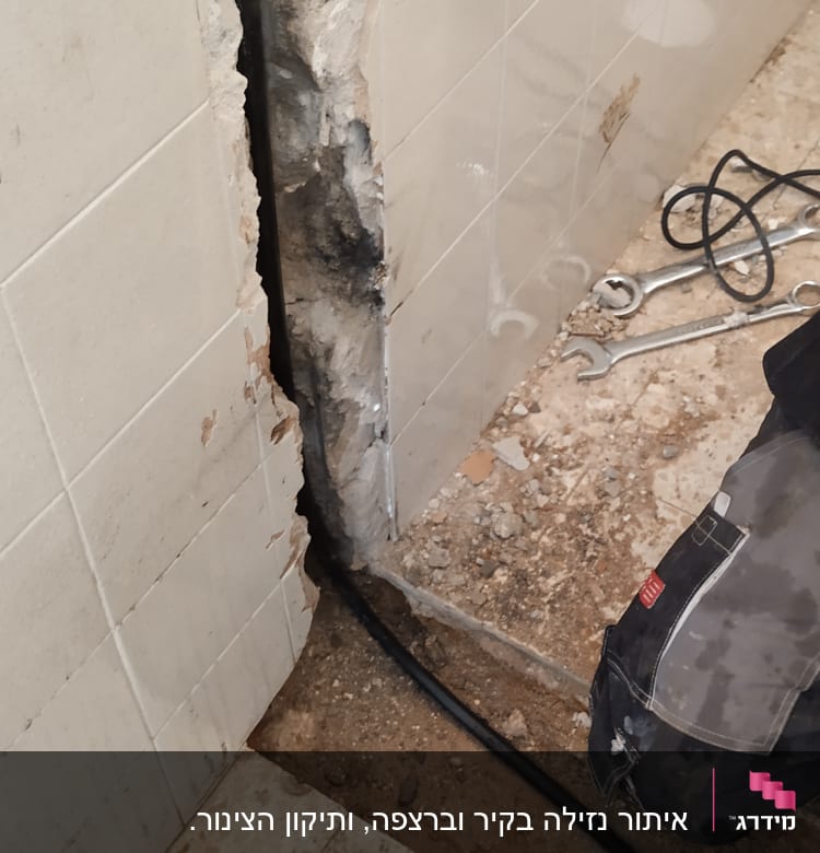קיר פתוח עם צינור וכלי עבודה של אינסטלטור